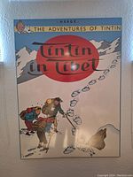 Photo of Tintin in Tibet poster showing illustrated characters trekking snowy terrain with large red sun and title text