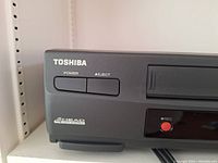 Close-up of the Toshiba VHS Player's left side with power and eject buttons, and 4 Head Hi-Fi Stereo label.