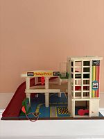 Front view of vintage Fisher Price garage showing ramps, play mat base, and Fisher Price decal.