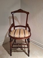 Front view of one wooden chair with carved top rail and striped upholstered seat.