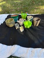 Photo of nine planters and mug laid on black and white blankets on grass surface, showing shapes, colors and condition.