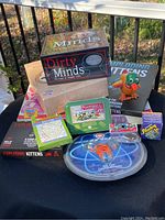 Overview of all items including board games, card games, wind-up duck, mini football game, wooden top, plastic game