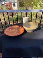 Image showing the Belize Maya plate, yellow ware bowl, and white ceramic vase on a black table with outdoors background.