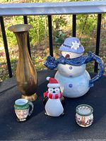 Photo showing entire lot of five items: snowman teapot, penguin salt shaker, brass vase, mini stein, and incense burner.
