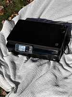 Top and front view of black HP Photosmart 5520 printer showing control panel and overall design.