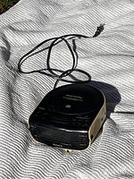 Top view showing the black Sony Dream Machine device with control buttons and power cord on a textured cloth surface.