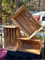 Three wooden nesting crates arranged stacked, showing the natural wood and handles on each crate's short side.