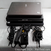 Three stacked laptops with three power cables in front, showing exterior condition and power cords.