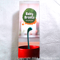 Front of the Baby Bronto tea infuser box showing blue dinosaur-shaped silicone infuser inside red cup illustration