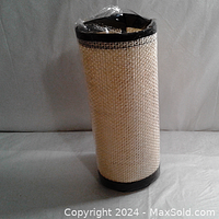Rolled up sisal hemp cat scratch pad wrapped in plastic, showing black edges and beige woven texture.