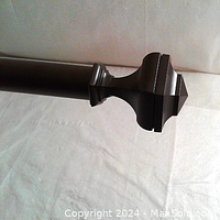 Close-up of the drapery rod showing the brown finish and hexagon finial detail.