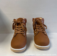 Front view of tan ankle boots, showing laces, padded collar, and white sole.