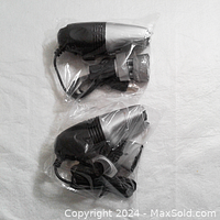 Two mini USB vacuum cleaners, each sealed in plastic packaging, showing the vacuum units with attached cables and general shape.