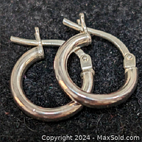 Close-up of the sterling silver chunky hoop earrings showing polished surface and latch closure.