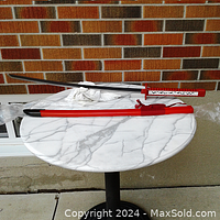 Full view of the samurai sword with red and black scabbard on a white cloth on marble table.