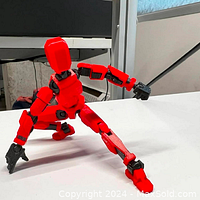 Assembled Titan 13 red action figure in a dynamic crouching pose showing its multi-jointed, adjustable limbs and hands with black finger details.