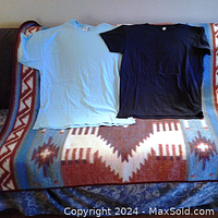 Two women's T-shirts laid flat on a patterned blanket, one light blue and one black