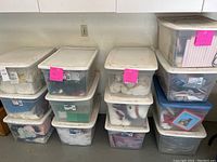 Photo of 13 clear plastic storage bins stacked against a wall containing holiday fabrics and items