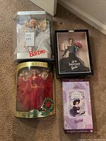 Four boxed special edition Barbie dolls arranged on carpet floor.