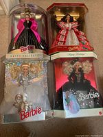 Four Barbie dolls in original holiday-themed display boxes, showing full packaging and doll details.