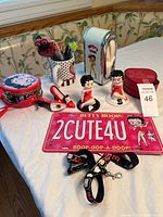 Full set of Betty Boop items arranged on table including salt and pepper shakers, novelty shoe, coffee mug, tin, license plate, lanyard, and napkin holder.