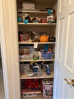 Full view of hallway closet shelves with various decor and storage items