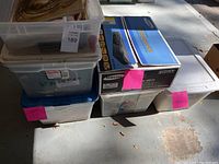 Photo of stacked clear Sterilite plastic bins with labels and a boxed DVD/VHS combo player on the right.