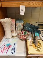 Overview photo of kitchen items showing white Lenox vase, small white vase, vintage pastel kitchen canisters, holiday Christmas decor, ceramic cutting board, oven mitts, and two decorative trays.