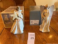 Front view of both Lladró angel figurines displayed beside their original boxes on a wooden table.