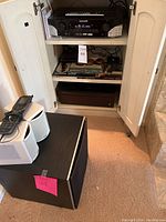 Overview of cabinet with audio equipment and subwoofer with speakers on floor
