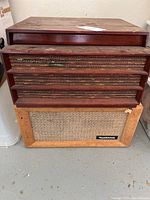 Wide angle photo showing a stack of vintage wood-cased audio equipment, with RCA Victor Radiophonic speaker at bottom featuring mesh front and wood slats.