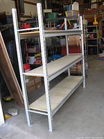 Three-quarter angled view showing the entire shelving unit with steel frame and three wooden shelves in a workshop space.