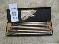 Set of 5 metallic valve guide reamers in a black metal box with yellowed paper label