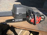 Side view of the Craftsman 18 inch chainsaw with attached bar and chain, showing the attached black plastic carrying case in the background.