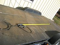 Photo showing the full length of the pressure washer wand extended on a trailer bed with attached black trigger handle and hose cord.