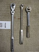 Photo of three hand tools laid on carpet: left Craftsman 11" flex head 3/8" ratchet, middle Craftsman 10" breaker bar, right 7" S K Wayne ratchet with knurled handle.