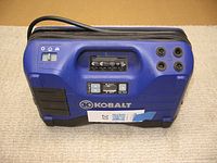Front view of Kobalt air compressor showing brand logo, power switch, pressure gauge, and adapter ports.