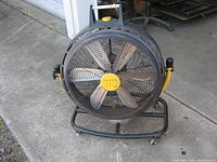 Front view of the 24-inch Lakewood portable floor fan with HSV brand and yellow center detail on blades, black circular protective grille, yellow handles on each side, black metal frame base with wheels.