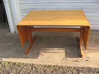Maple drop leaf trestle table with wings down, showing light maple wood and trestle base structure.