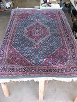Overall top view of the hand-knotted wool rug showing full pattern and color scheme of red, blue, green, white, and black.