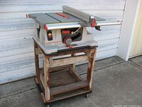 Full view of the Ridgid 10-inch portable table saw set on a wooden cart with wheels outdoors.