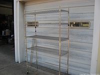 Front view of NSF rolling wire shelf cart with five shelves and caster wheels in front of a garage door.