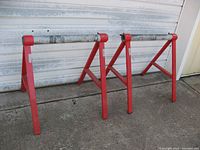 Pair of red powder coated steel sawhorses with gray schedule 80 PVC tops, showing overall condition and structure.