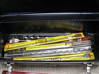 Photo showing various drill bits with yellow 'industrial quality' packaging, some loose metal bits, inside a black metal toolbox compartment