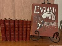 Photo of the 'England Illustrated' cloth-bound book showing elaborate embossed cover with silver and colored details.