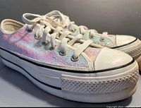 Side angle showing the thick platform sole, shimmery fabric upper, white laces and toe caps.