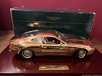 Gold plated Aston Martin DB7 model on wooden base with original box behind