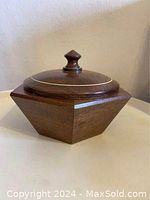Closed walnut bowl with lid featuring gold accent line and knob handle on top