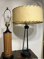 Side view of mid century lamps showing walnut base lamp and hairpin base lamp with rawhide stitched shade.