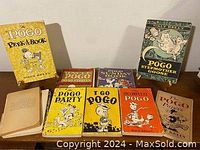 Eight Pogo comic books and related titles arranged showing front covers, colorful cartoon illustrations, mostly yellow covers.